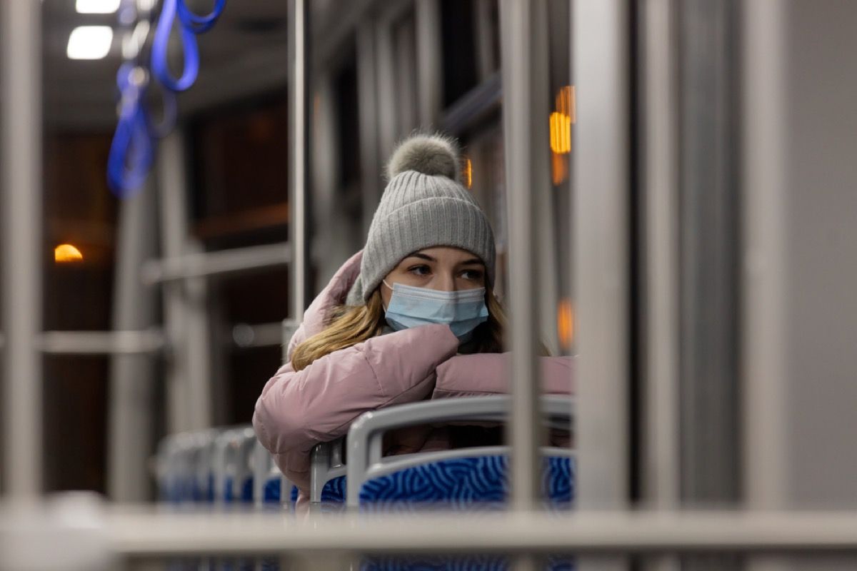 kvinne i vinterklær og ansiktsmaske på en buss