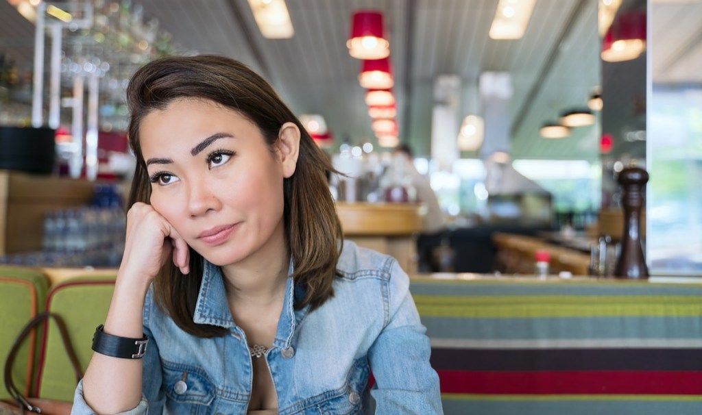 người phụ nữ trẻ châu Á nhìn khó chịu và đảo mắt vào một quán ăn