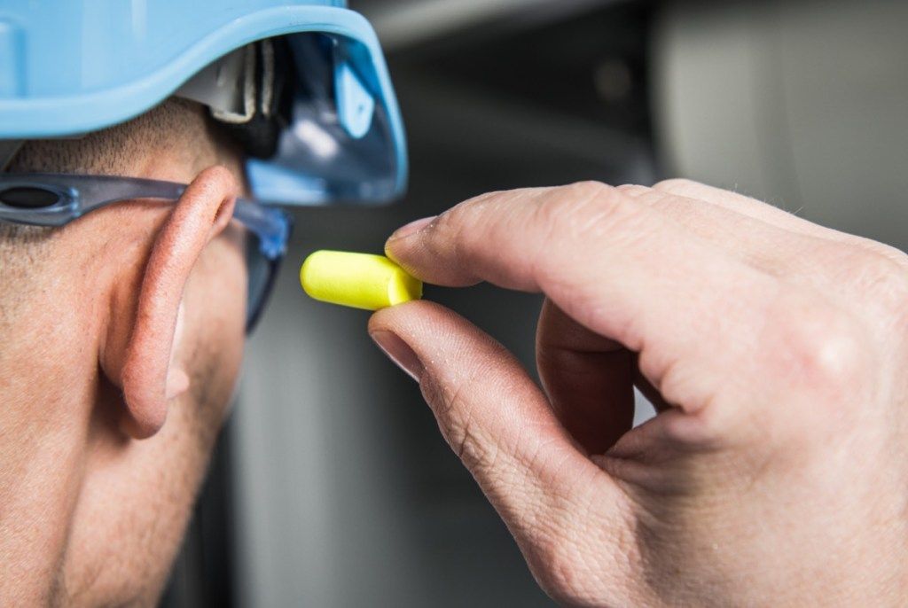 Mężczyzna zakładający zatyczki do uszu zapobiega starzeniu się problemów zdrowotnych