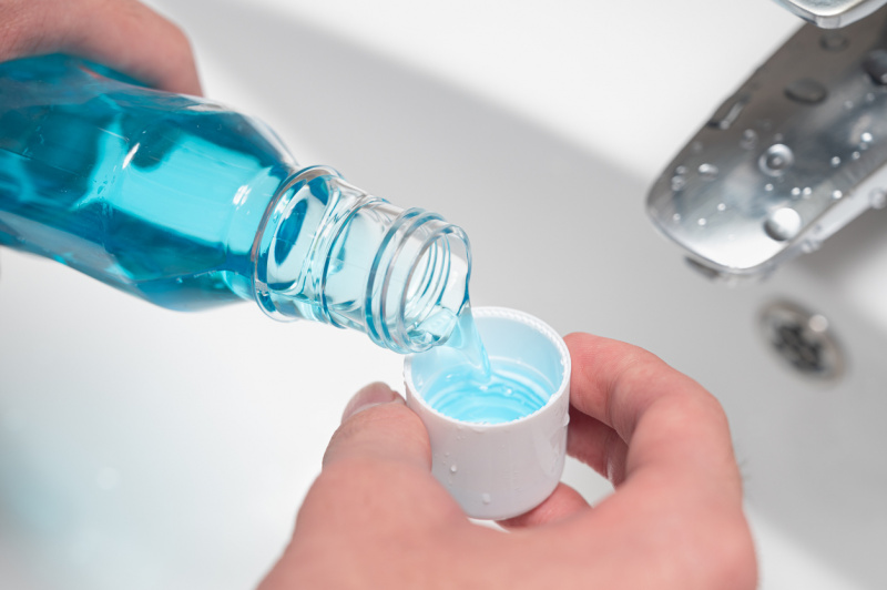   Ručné nalievanie fľaše ústnej vody do uzáveru.