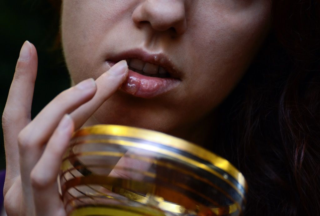 uma mulher aplicando azeite de oliva nos lábios