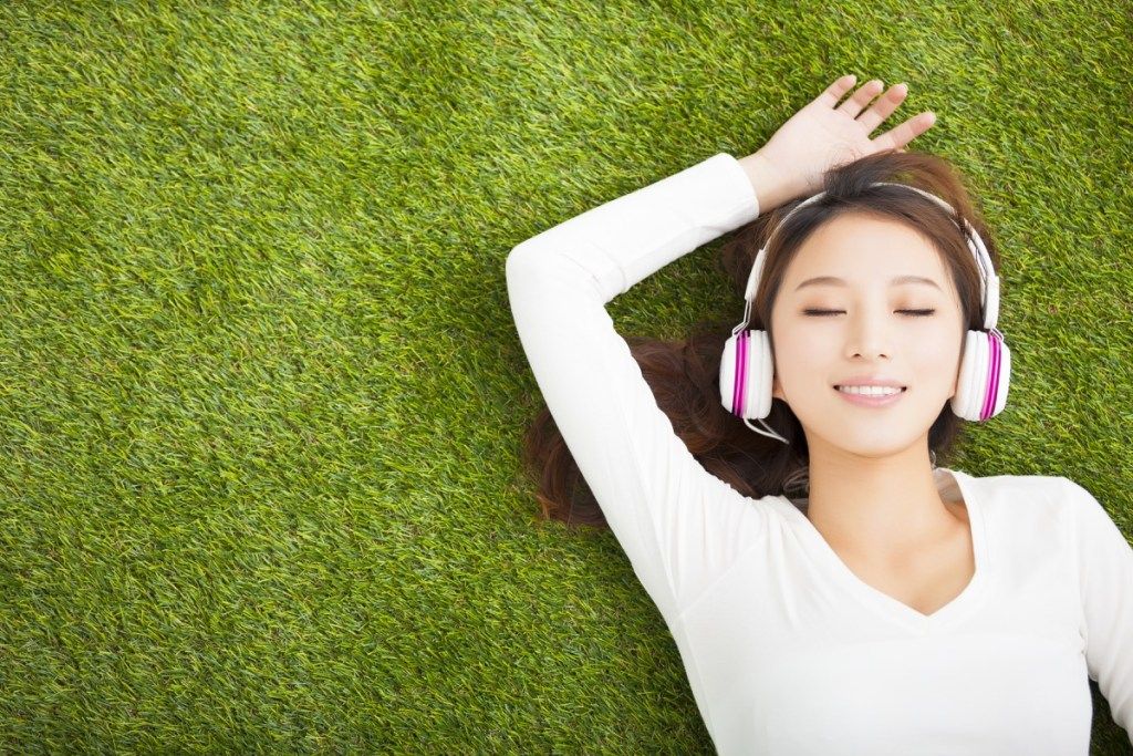मानसिक स्वास्थ्य के लिए व्यायाम पर हेडफ़ोन के साथ संगीत सुनती महिला