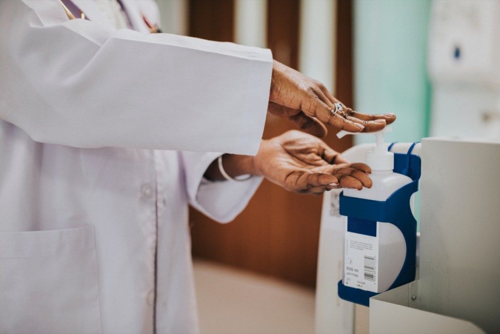Sievietes ārsts, izmantojot roku sanitāriju slimnīcas roku sanitizer baktērijās