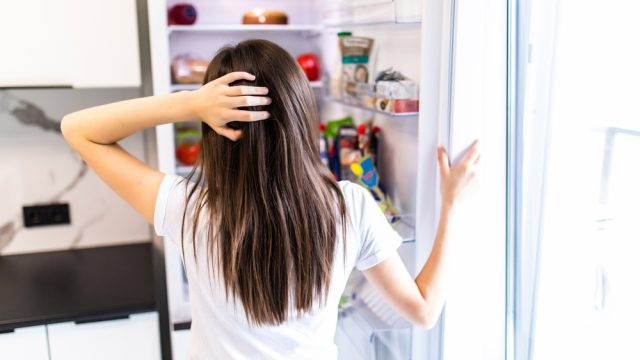   Una mujer busca comida en su refrigerador o congelador