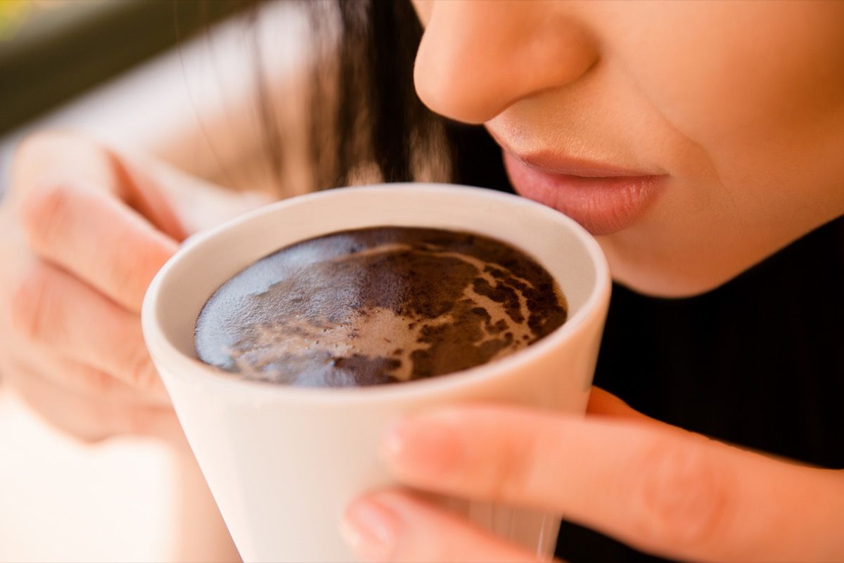 عورت ایک کپ کافی کا بو سونگھ رہی ہے