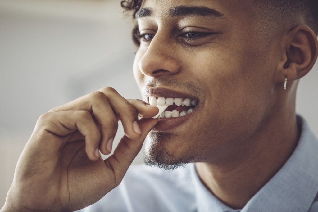 Zwarte man kauwgom aanbrengend zijn mond