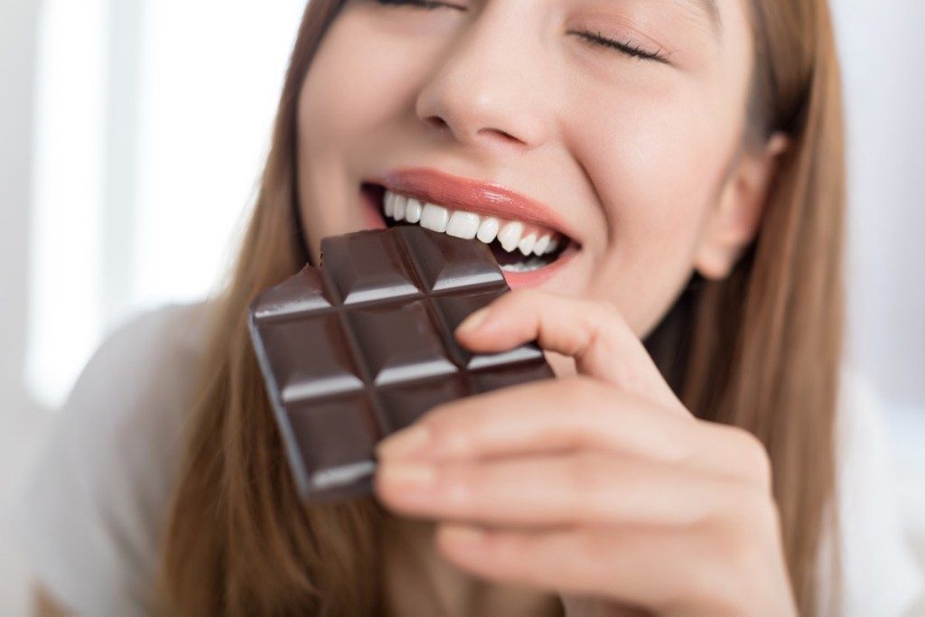Vrouw die van een chocoladereep geniet