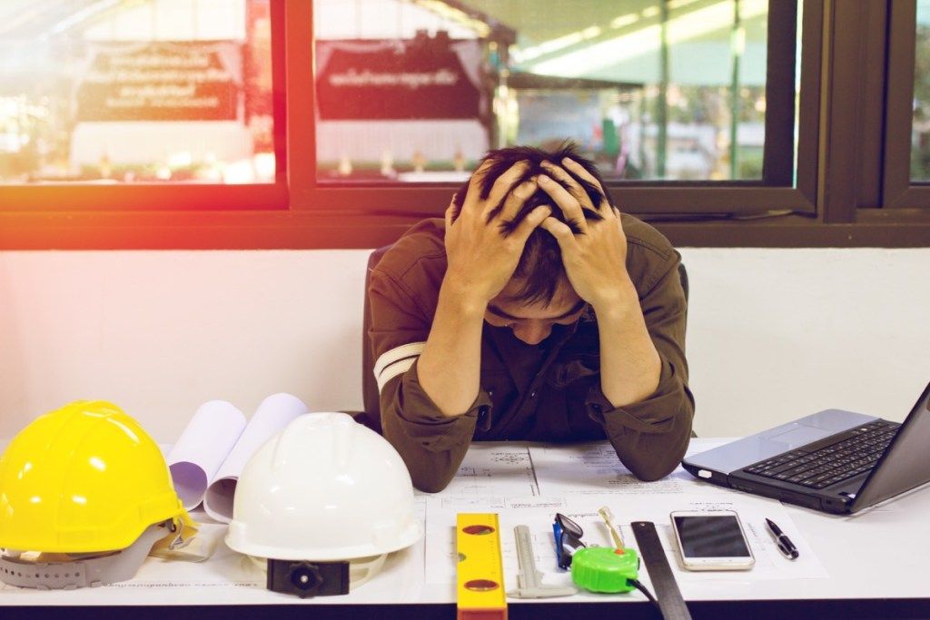 Човекът се стресира на бюрото си на работа, евентуално мениджър на строителството