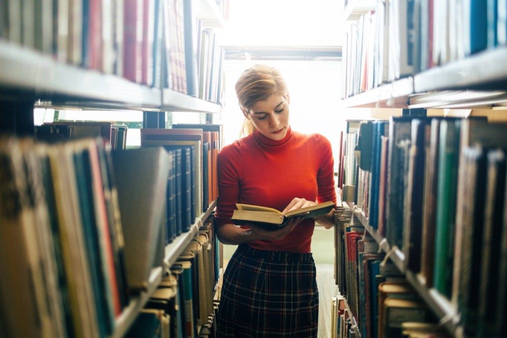 femme lisant un livre dans une bibliothèque