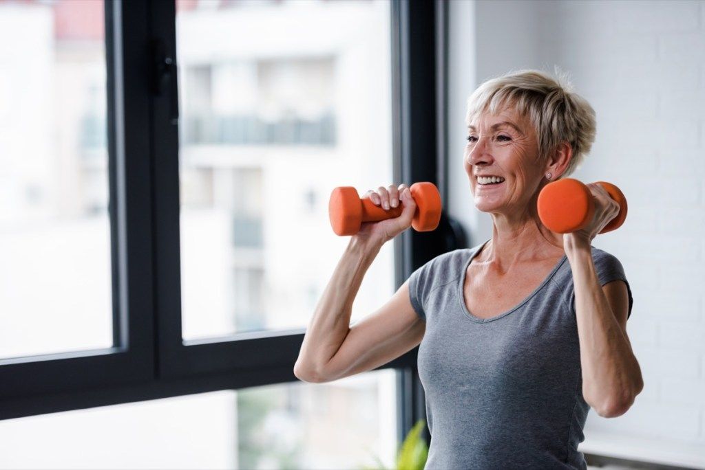 Mujer de edad avanzada levantando pesas y haciendo ejercicio en el gimnasio
