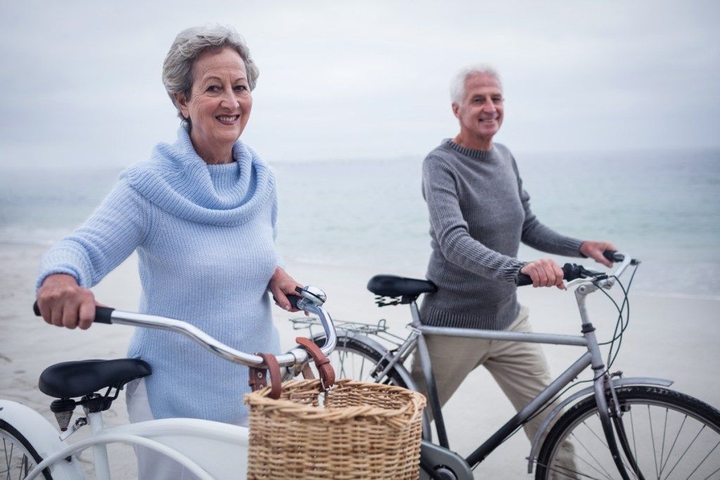 Ηλικιωμένο ζευγάρι πηγαίνει για ποδήλατο σε διακοπές κοντά στην παραλία