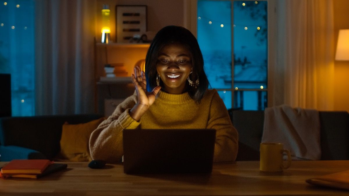 mlada crnka koja maše svojim računalom tijekom videochatova noću