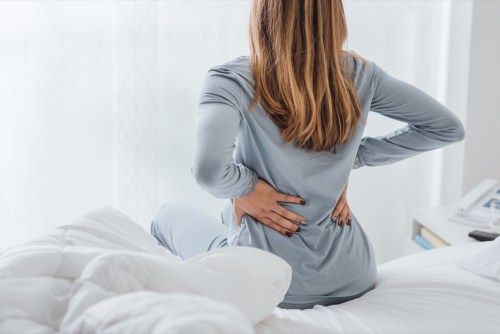 Sieviete ar muguras sāpēm no gulēšanas uz vēdera