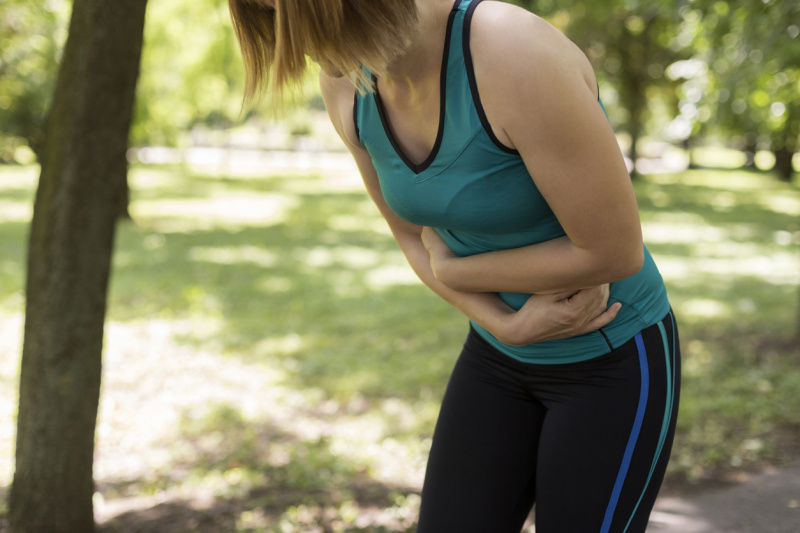  Žena v cvičebnom úbore si drží brucho.