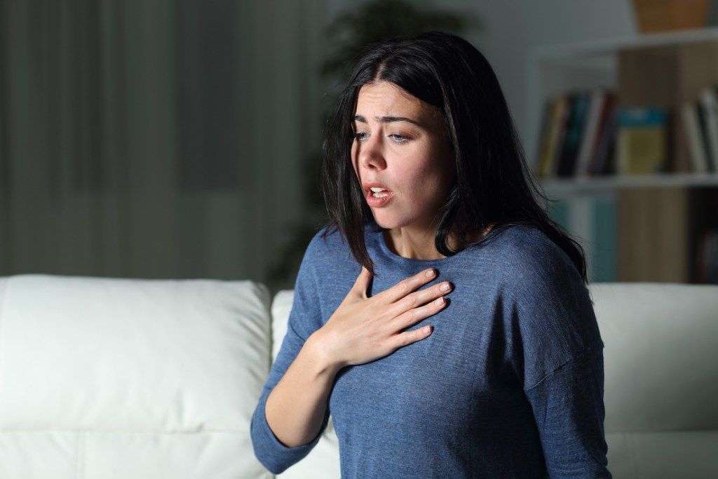 Frau allein im Haus in der Nacht hat Hand auf der Brust, als sie versucht zu atmen