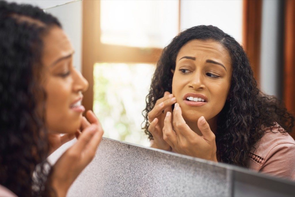 Moteris veidrodyje tikrina savo odą