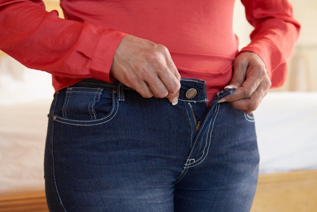 Người phụ nữ cố gắng cài khuy quần jean tăng cân