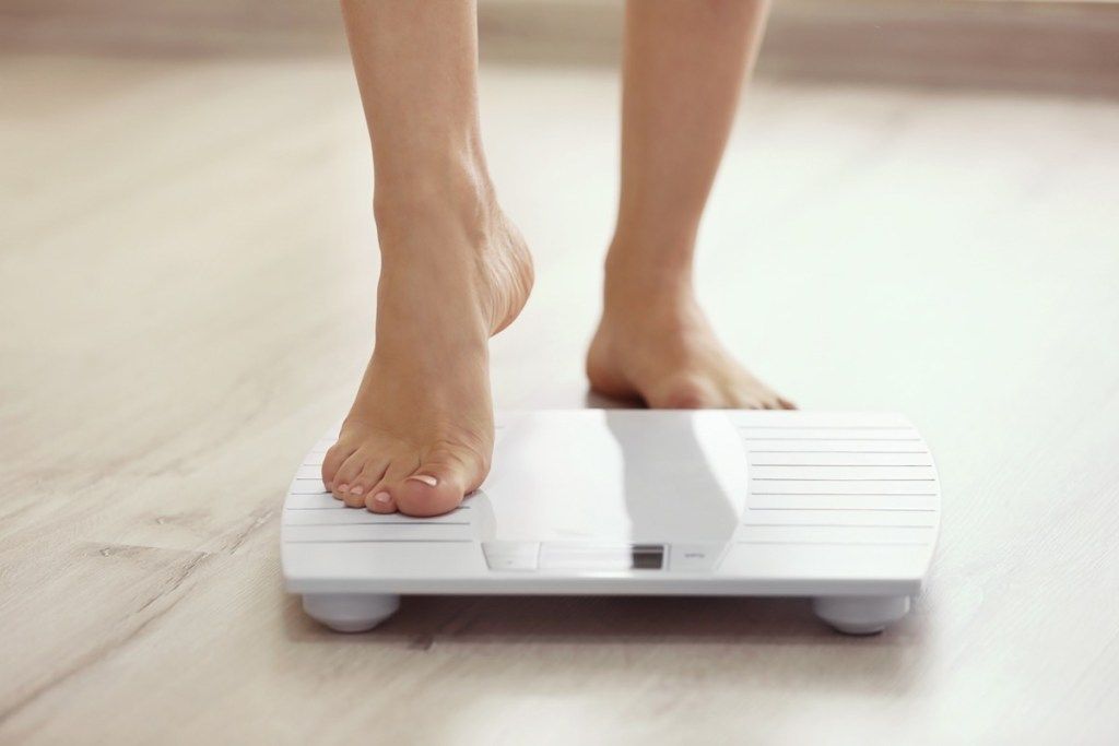 عورت اپنے وزن کے ل a ایک پیمانے پر قدم رکھ رہی ہے