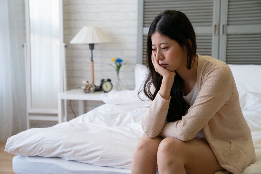 Femeie care pare tristă și deprimată în pat