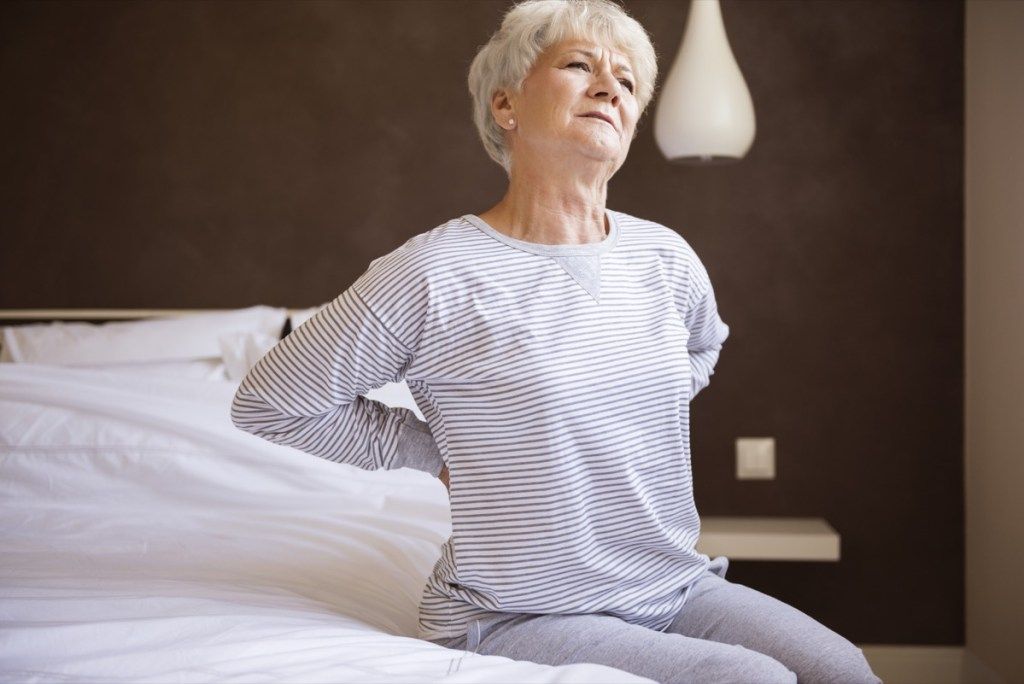 אישה לבנה מבוגרת עם כאבי גב במיטה