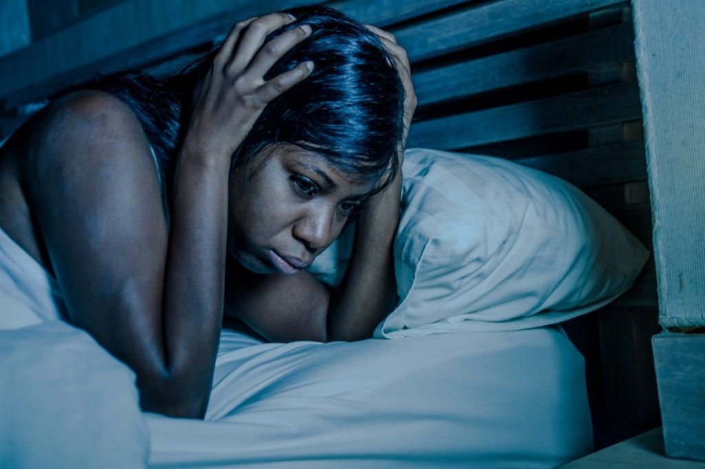 Ženska budna in žalostna v postelji
