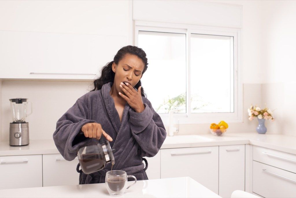 커피를 붓는 동안 하품하는 여자