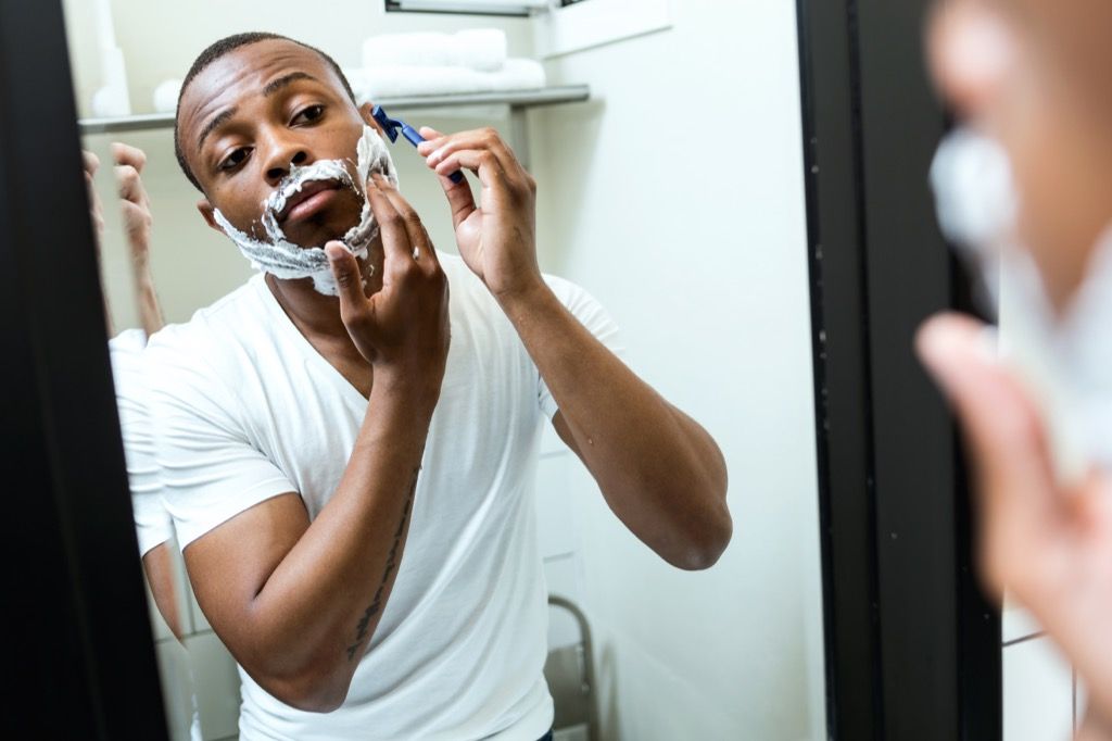 svart mann som barberer seg i speilet