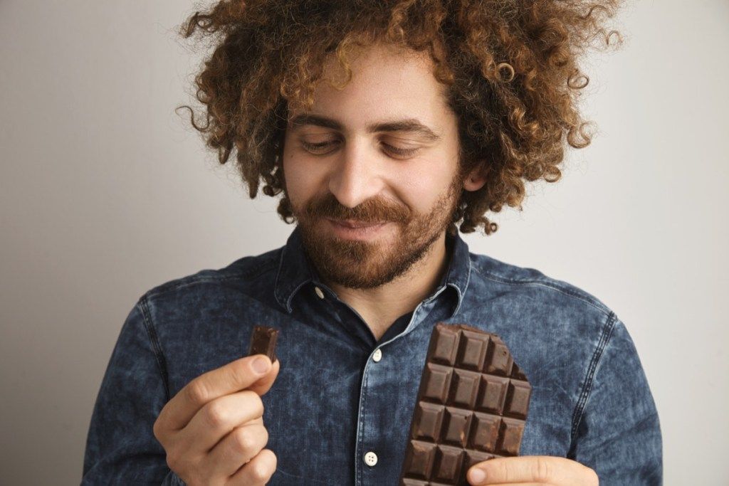 Mann som spiser firkanter med sjokolade