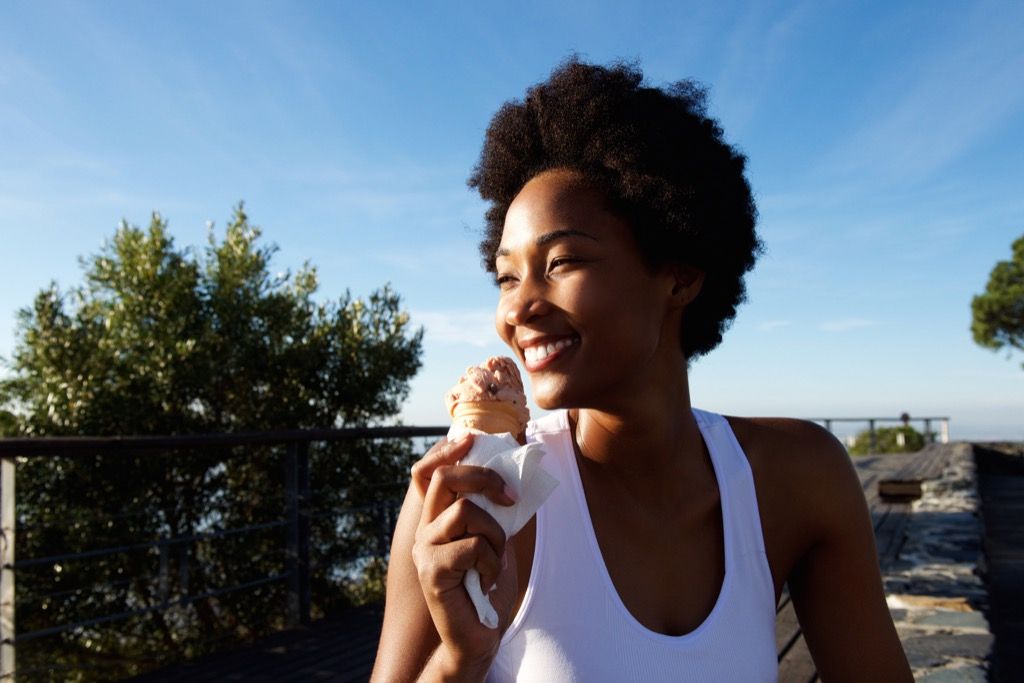 אישה כהה יותר אוכלת גלידה על החוף