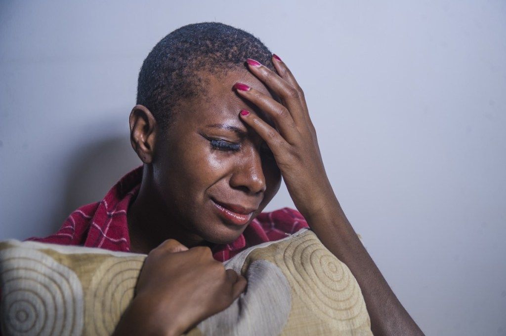 juodaodė moteris, verkianti ir įsikibusi į pagalvę
