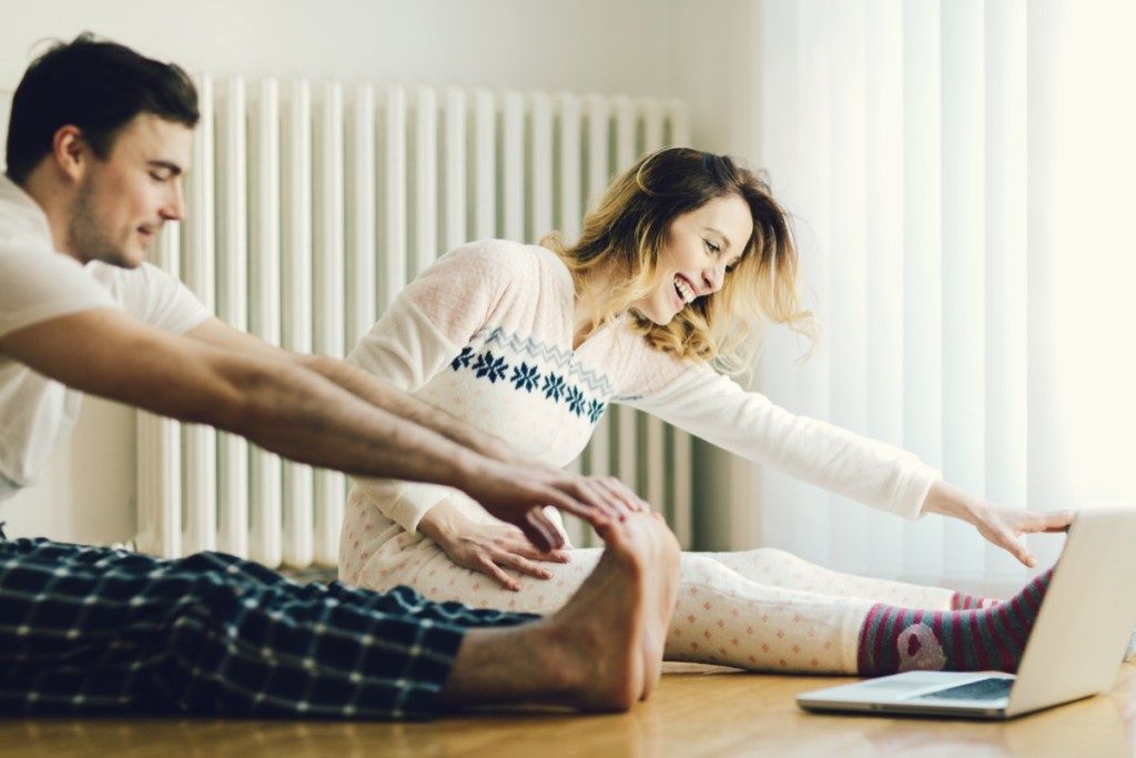 זוג מאושר עושה מתיחות ומתאמן בבית