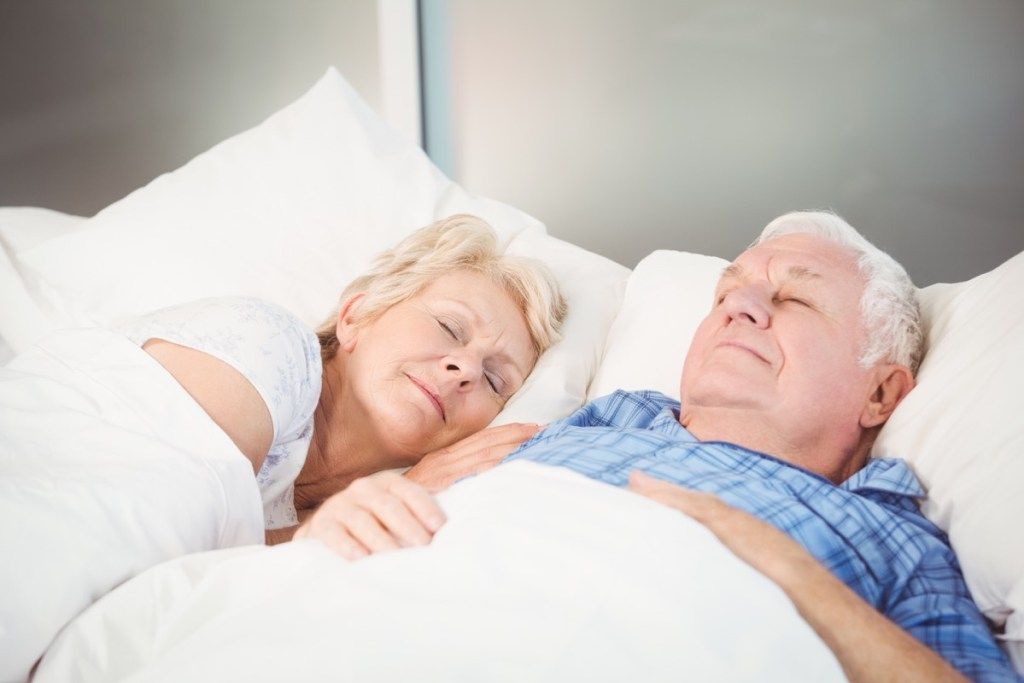 Pasangan senior tidur di tempat tidur