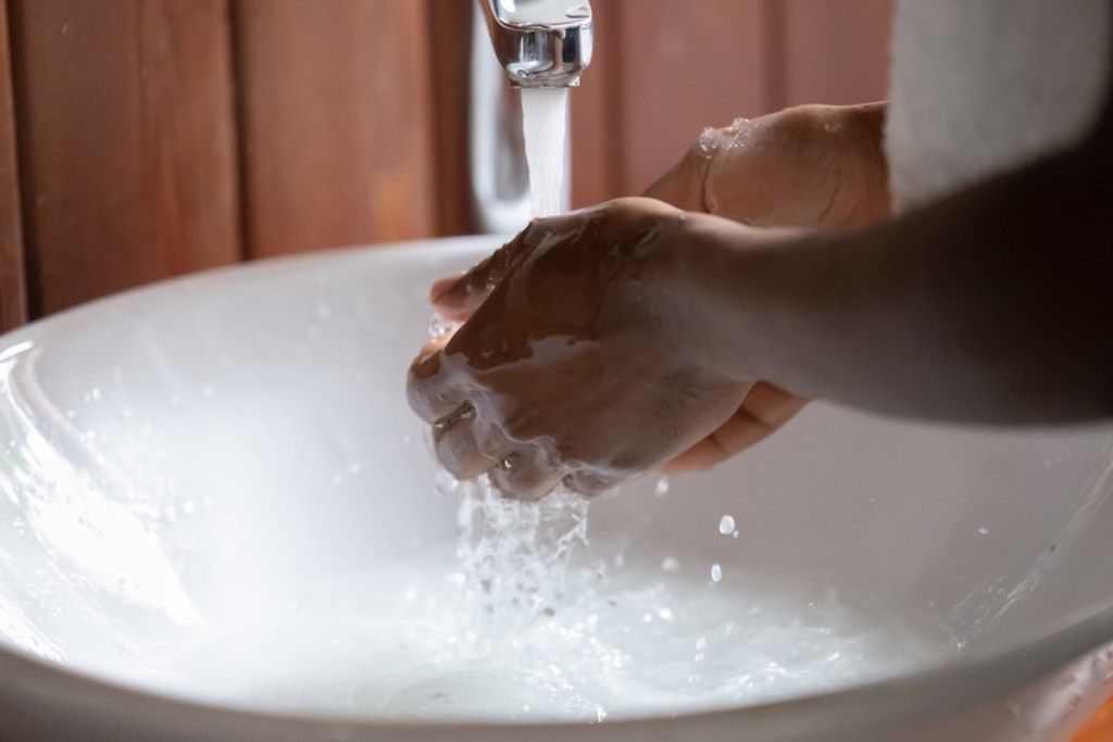 Schwarze Person, die ihre Hände in einem Waschbecken wäscht