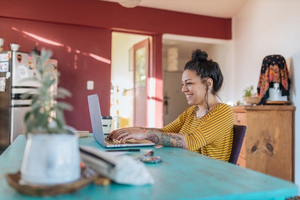 nainen työskentelee kannettavalla tietokoneella kotona