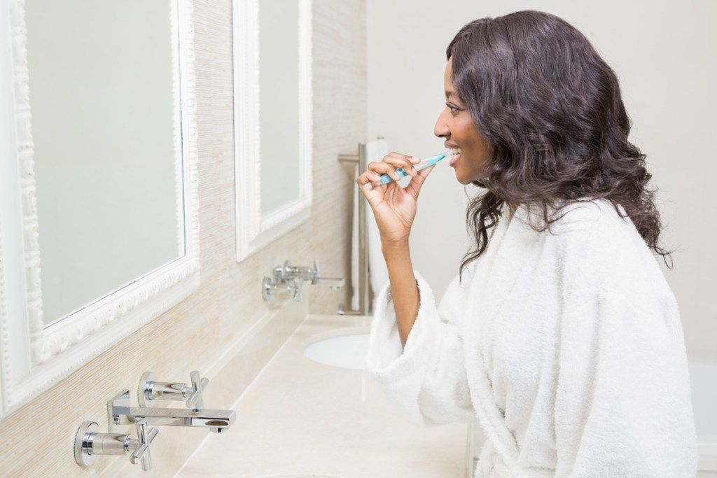 Чернокожа жена, която си мие зъбите в банята