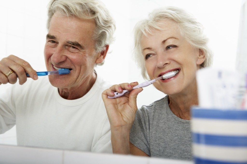Пожилая пара чистит зубы в ванной