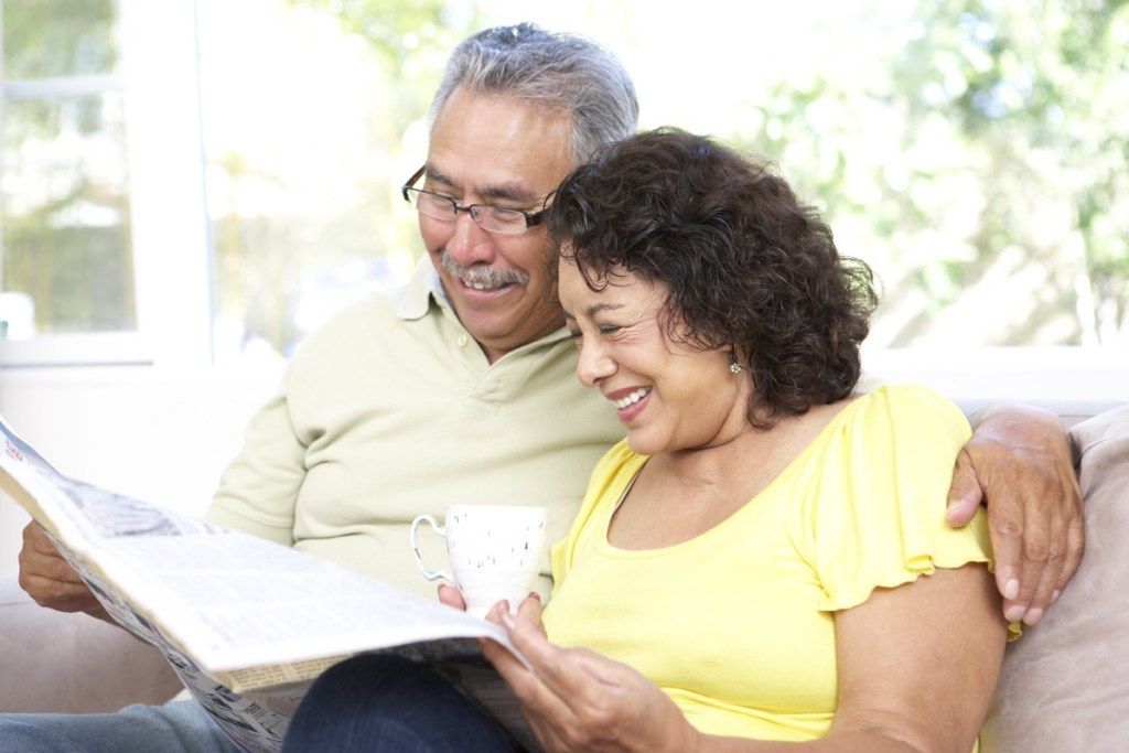 Äldre par som lyckligt läser tidningen