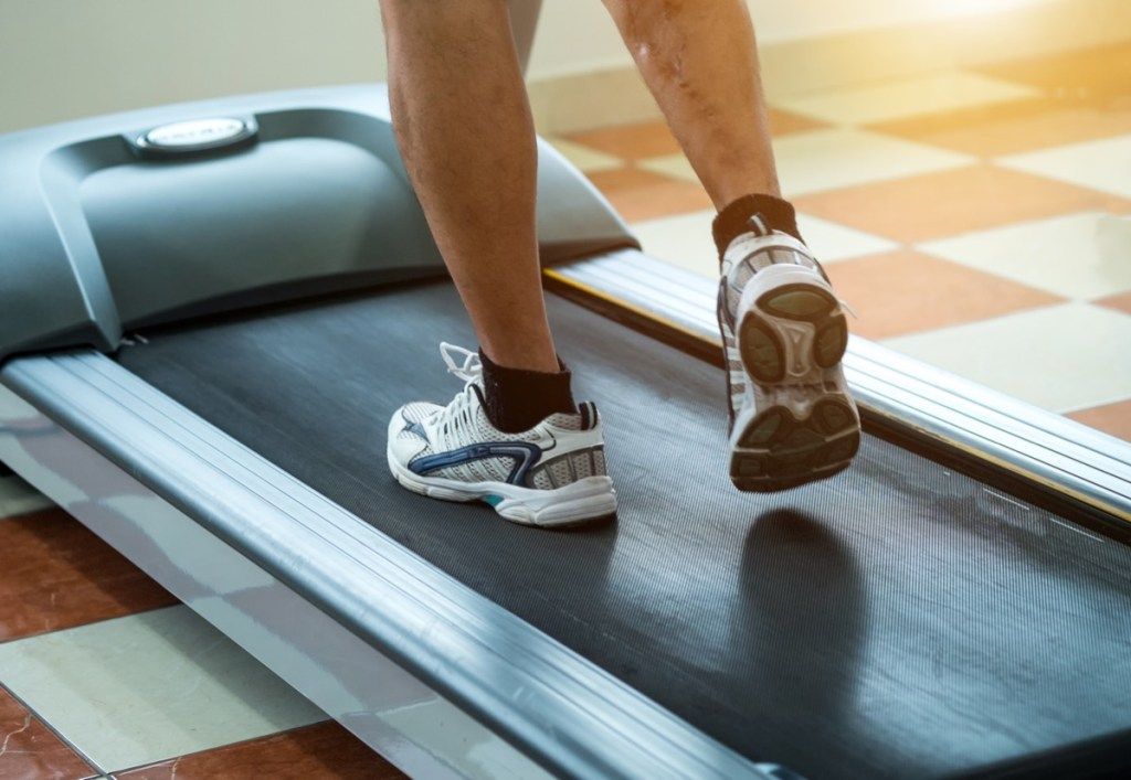 Pria yang berlari di treadmill di gym
