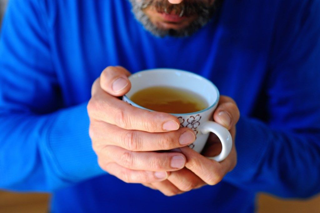 Szakállas férfi zöld teát iszik egy bögréből