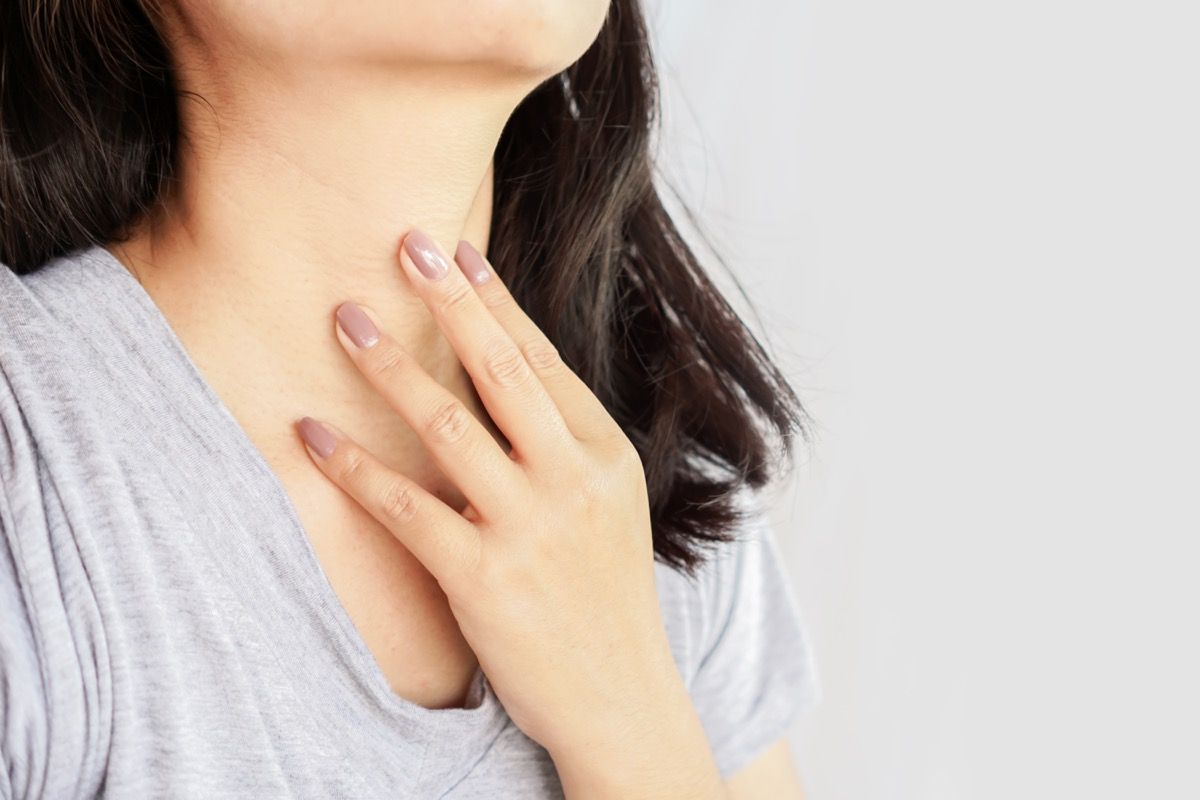 tangan wanita memeriksa kelenjar tiroid di lehernya