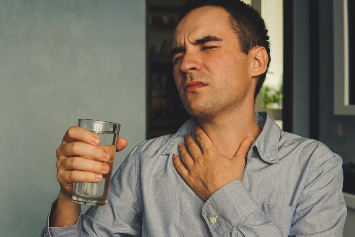 Човек пие вода за лечение на сухота в гърлото