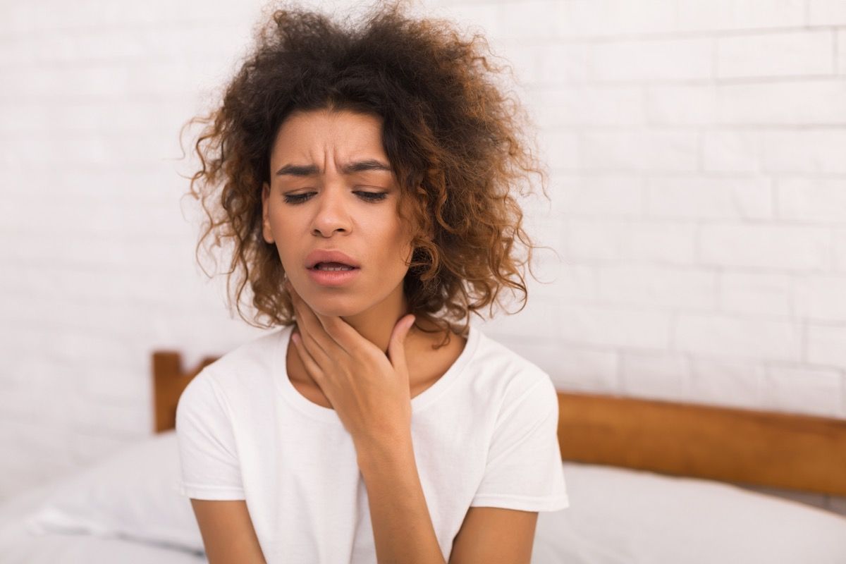 Mulher segurando a garganta por causa de gotejamento pós-nasal