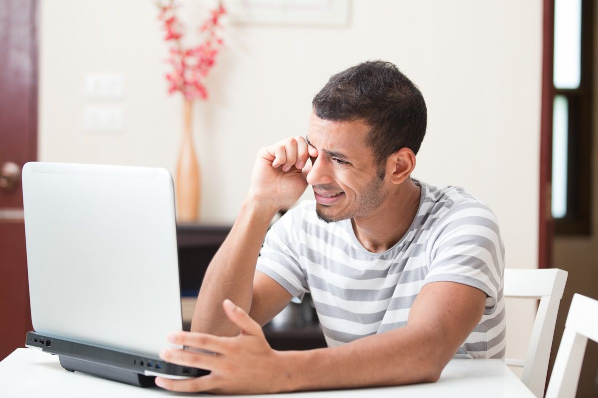 Hombre con visión borrosa entrecerrando los ojos ante la pantalla de su computadora