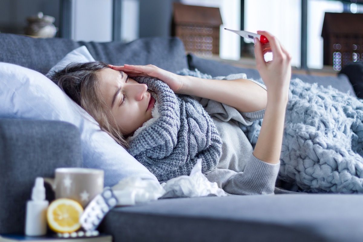 Wanita berbaring di sofa dengan demam dan menggigil