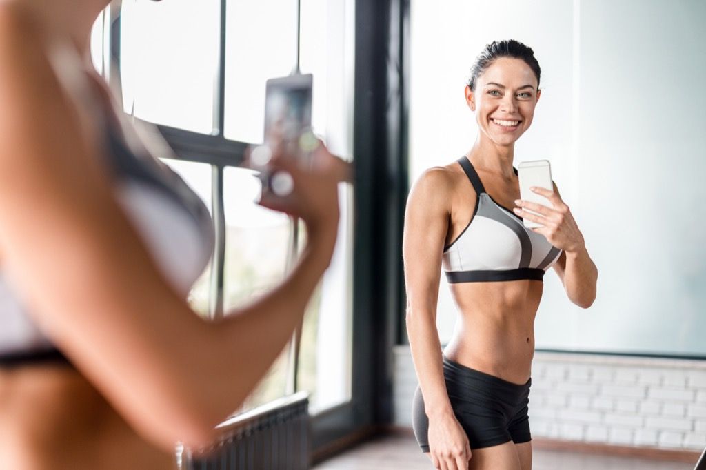 wanita kecergasan berpose untuk selfie di cermin