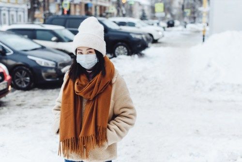 người phụ nữ đeo mặt nạ và mặc quần áo mùa đông bên ngoài tuyết