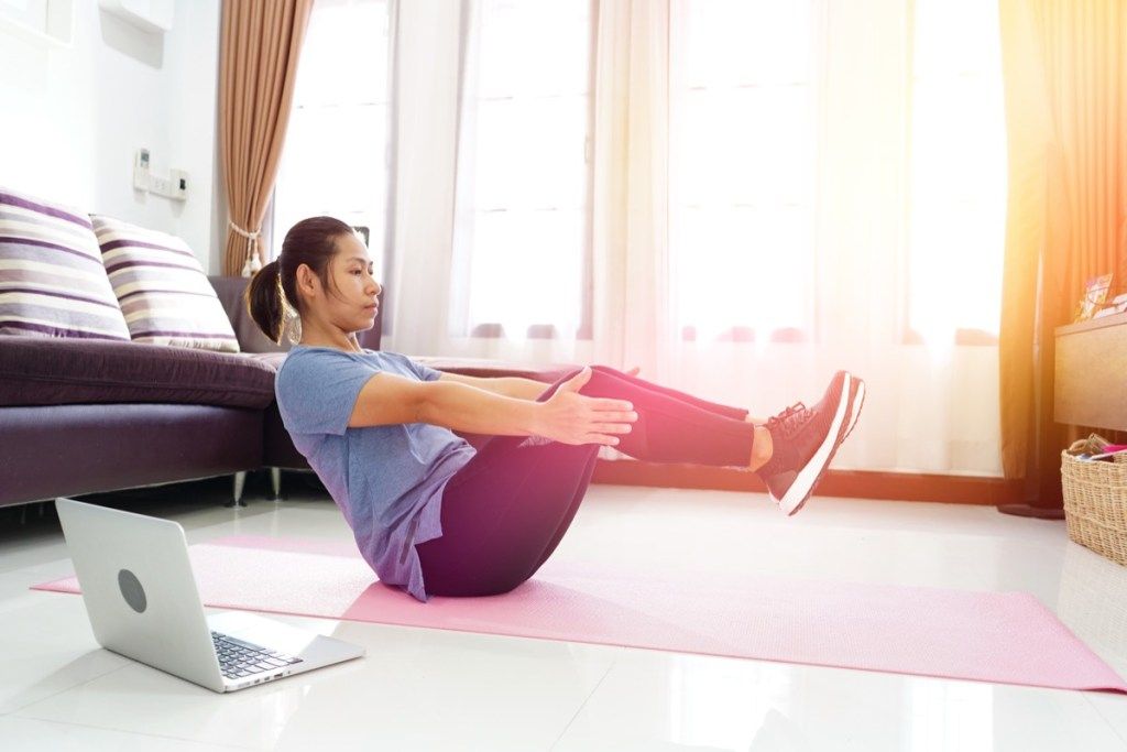 Žena, která dělá cvičení cvičení ab v obývacím pokoji