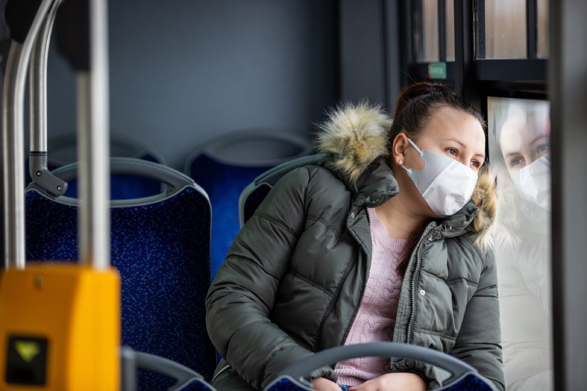 жена са заштитном маском која гледа кроз прозор у аутобусу