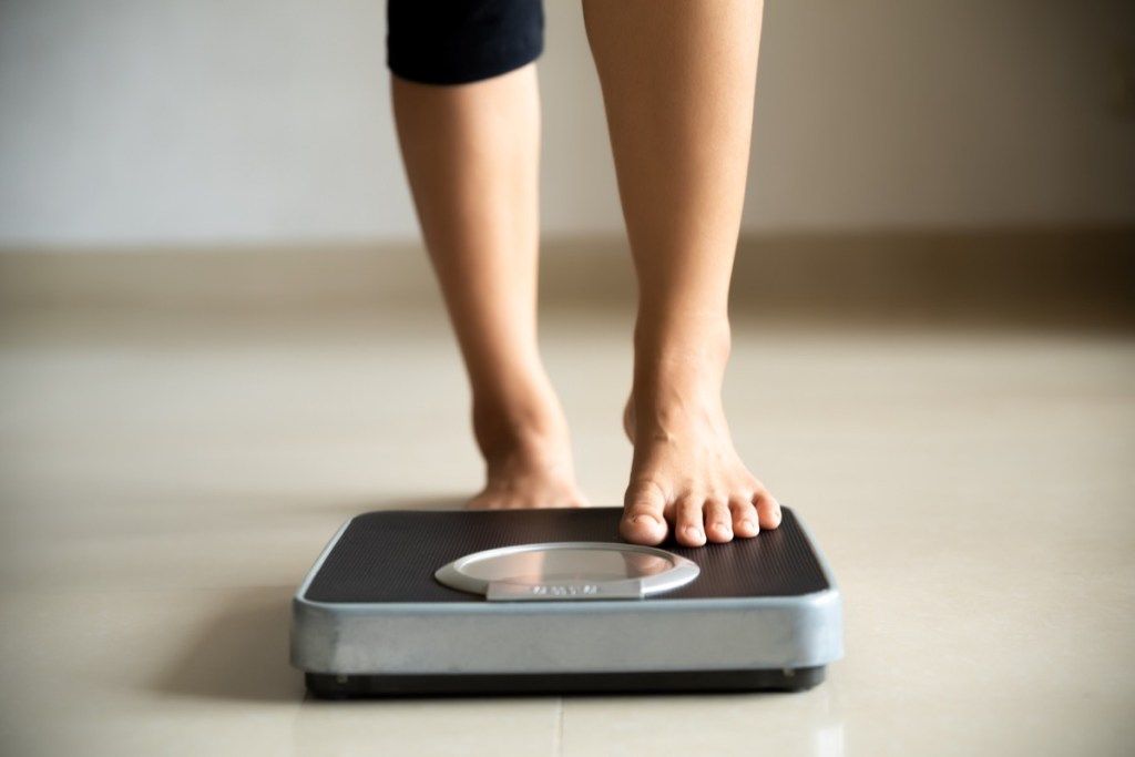 وزن کم کرنے کے لئے عورت پیمانے پر قدم رکھ رہی ہے