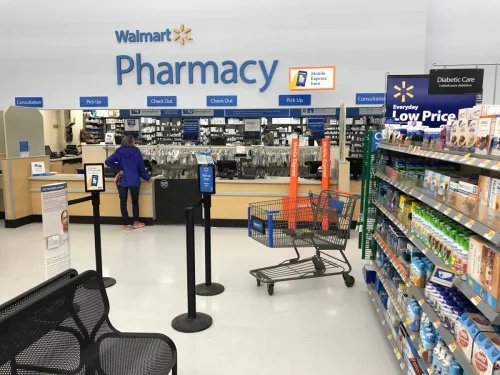   Ảnh chụp phía trước của hiệu thuốc tại Walmart. Một khách hàng chờ lấy hàng.